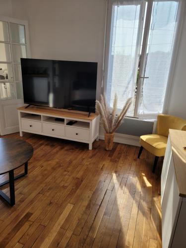 Appartement cosy في Saint-Martin-Longueau: غرفة معيشة مع تلفزيون بشاشة مسطحة وأريكة