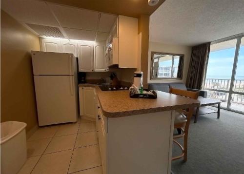 a kitchen with a white refrigerator and a table with chairs at Outrigger Beach Club Resort in Ormond Beach