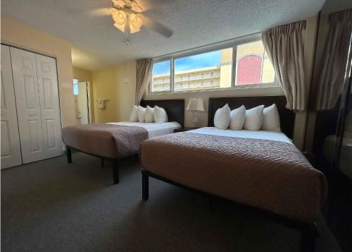 a hotel room with two beds and a window at Outrigger Beach Club Resort in Ormond Beach
