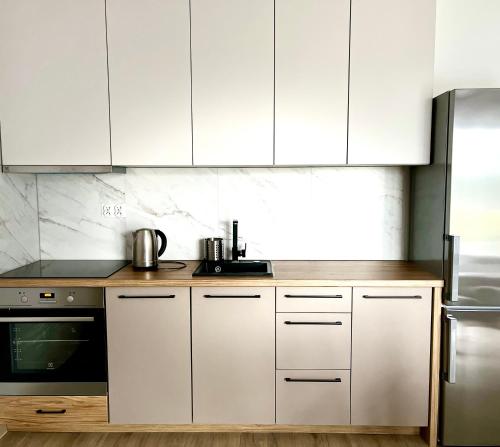 a kitchen with white cabinets and a stove at Apartamenty Lobeliowy Port in Borzyszkowy