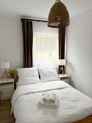 a bedroom with a bed with towels and a window at Apartamenty Lobeliowy Port in Borzyszkowy
