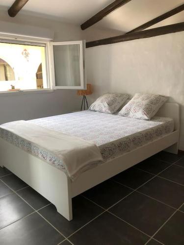 - un lit blanc dans une chambre avec fenêtre dans l'établissement Logement insolite au coeur d'une écurie, à Arles