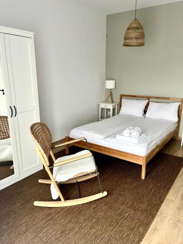 a bedroom with a bed and a rocking chair at Apartamenty Lobeliowy Port in Borzyszkowy