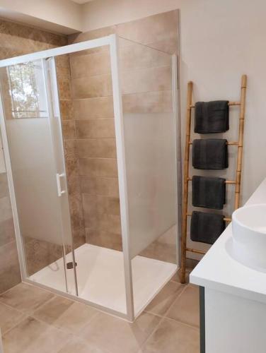 une douche avec une porte vitrée dans une salle de bain dans l'établissement Charmante maison avec jardin aux portes des gorges de l'Ardèche, à Saint-Julien-de-Peyrolas