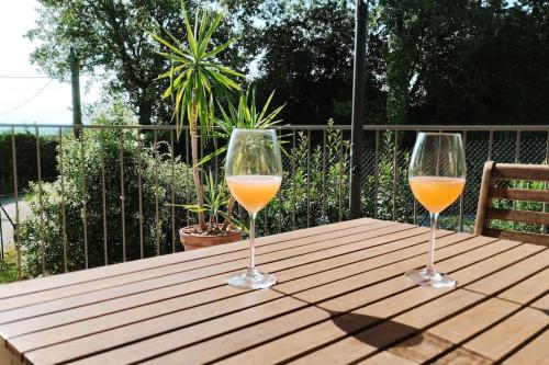 deux verres de vin orange posés sur une table en bois dans l'établissement Charmante maison avec jardin aux portes des gorges de l'Ardèche, à Saint-Julien-de-Peyrolas