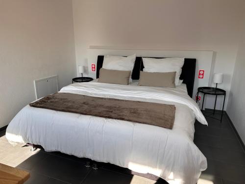 um quarto com uma cama grande com lençóis brancos e almofadas em Ferienzimmer Frank em Niederalteich
