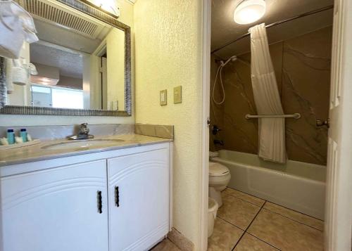 a bathroom with a sink and a toilet and a mirror at Outrigger Beach Club Resort in Ormond Beach