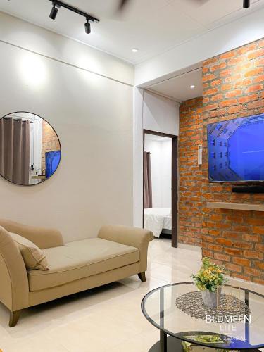 un soggiorno con divano e TV su un muro di mattoni di Blumeen Lite 1 - Comfortable Budget Home 3BR a Kuala Terengganu