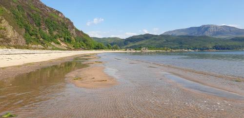 a sandy beach with mountains in the background at Tigh na Camus in Glenelg