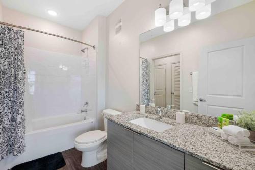 a bathroom with a sink and a toilet and a mirror at Lavish 2BR Apartment in Tampa in Tampa