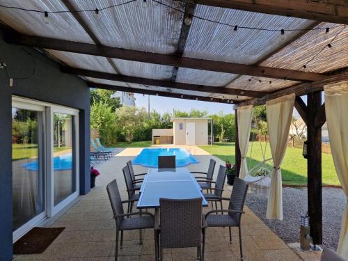 patio ze stołem i krzesłami oraz basenem w obiekcie Villa Makale w mieście Umag