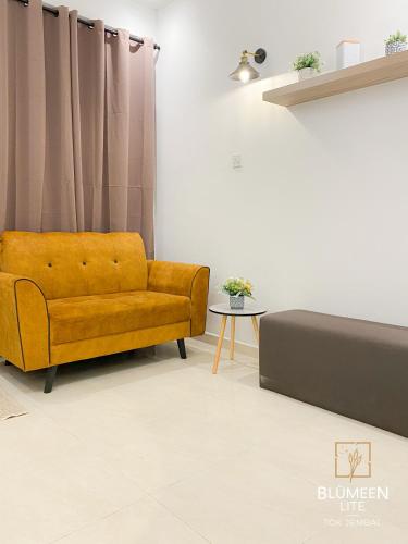 a living room with a yellow couch and a table at Blumeen Lite 1 - Comfortable Budget Home 3BR in Kuala Terengganu
