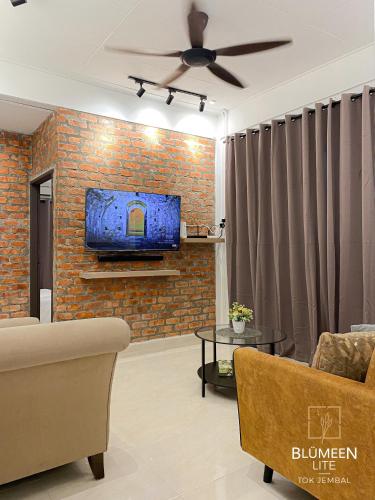 ein Wohnzimmer mit einem Sofa und einem TV an einer Backsteinwand in der Unterkunft Blumeen Lite 1 - Comfortable Budget Home 3BR in Kuala Terengganu