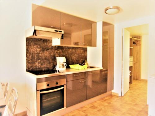 - une cuisine avec des placards bruns et une cuisinière dans l'établissement LA ORANA, à Frontignan