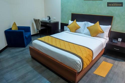 a bedroom with a large bed and a blue chair at Hotel The Black Stone in Bangalore