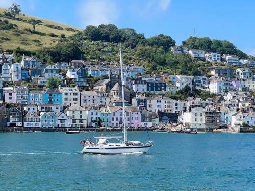 een boot in het water voor een stad bij Dartmouth Town Centre 2 bedroom stylish apartment is perfect for families and couples with a happy & homely feel being only 30 meters from the sea but set back & quiet with everything on the doorstep a gorgeous place to explore the Devon beaches 5 star FB in Dartmouth