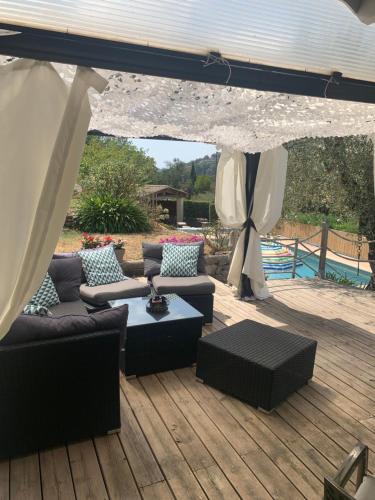 a patio with couches and a table on a deck at Chalet de charme tout confort in Les Adrets de l'Esterel