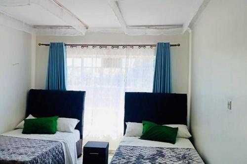 um quarto com 2 camas e uma janela com cortinas azuis em R&B Retreat house in Rodi Kopany - Homabay County, Kenya, Africa em Marinde