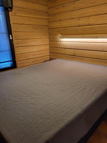 Cama en habitación de madera con ventana en Tunturipöllö 4, en Ruka