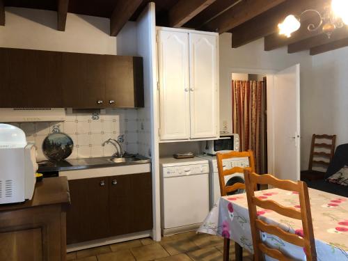 a kitchen with white cabinets and a table in a room at SUPER LIORAN LA MAISONETTE à 5 km de la station in Saint-Jacques-des-Blats