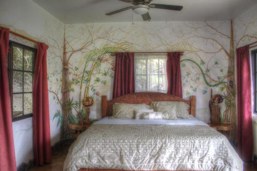a bedroom with a bed with a tree mural at Gingerbread Restaurant & Hotel in Nuevo Arenal