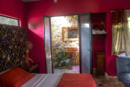 a red bedroom with a bed and a stone wall at Gingerbread Restaurant & Hotel in Nuevo Arenal