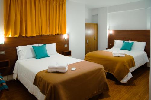 a hotel room with two beds with yellow and blue pillows at La Posada D'Benjamín in Oxapampa