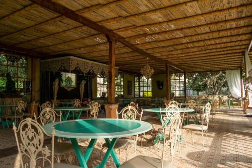 eine Terrasse mit Tischen und Stühlen und einer Holzdecke in der Unterkunft Hacienda Santa María de Cieneguilla in Cieneguilla