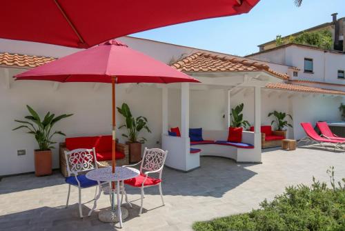 a patio with chairs and a table with a red umbrella at Maison Kalea in Sorrento