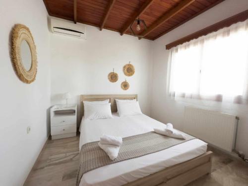 1 dormitorio con 1 cama con sábanas blancas y ventana en Villa Aelia en Kámpos