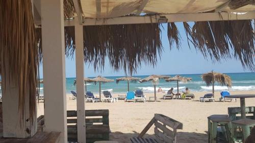 una playa con sillas y sombrillas y el océano en El Huerto, en Valencia