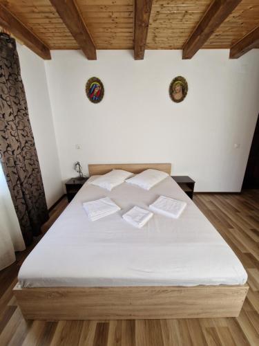 um quarto com uma cama com lençóis brancos e tectos em madeira em Pensiunea agroturistica "Cheile Cibului" em Cib