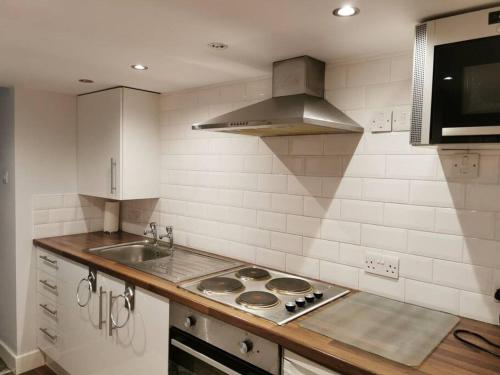uma cozinha com um lavatório e um fogão forno superior em Private garden apartment with secure parking em Southport