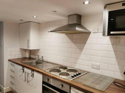 a kitchen with a sink and a stove top oven at Private garden apartment with secure parking in Southport