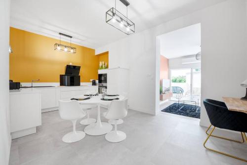 une cuisine blanche avec une table et des chaises dans une pièce dans l'établissement Bel appartement en centre ville, à Albi