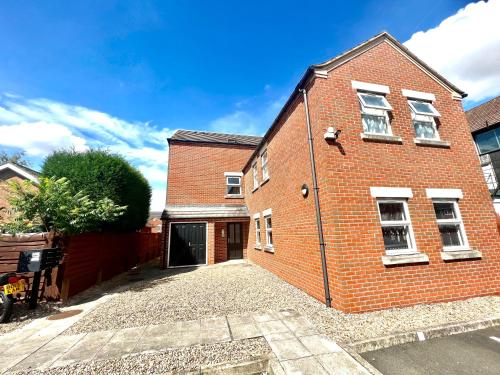 a red brick house with a driveway in front of it at Cosy apartment in town centre in Finedon