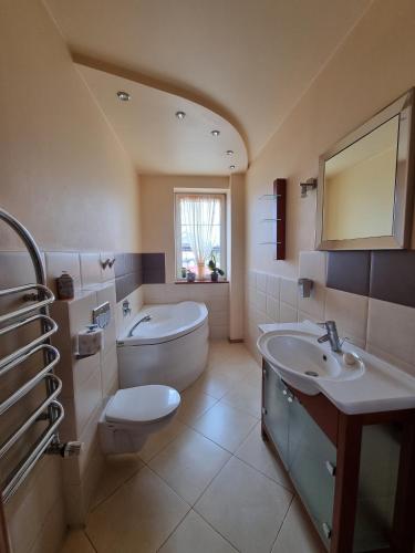 a bathroom with a toilet and a tub and a sink at Darłowska 49A in Dąbki