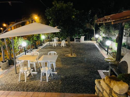 a group of tables and chairs under an umbrella at night at Le Maioliche in Saponara Villafranca