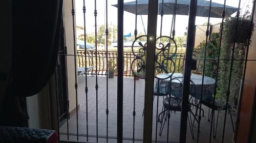 an iron gate with a table and an umbrella on a patio at A Santy's House 1piano no lift no shuttle solo parcheggio in strada 5 minuti da fermata bus per da fiera di roma nessun pasto no meal, air condiz ed extra bed FOR A FEE A PAGAMENTO in Fiumicino