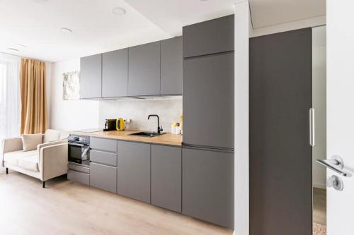 a kitchen with gray cabinets and a couch at Ozo eco apartments in Vilnius