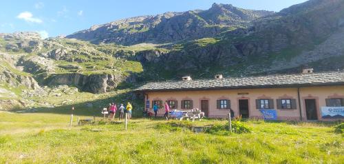 un grupo de personas parados fuera de una casa en una montaña en Rifugio Casa di Caccia en Noasca