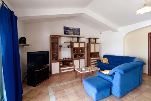 uma sala de estar com um sofá azul e uma televisão em Incantevole attico con grande terrazza em Anzio