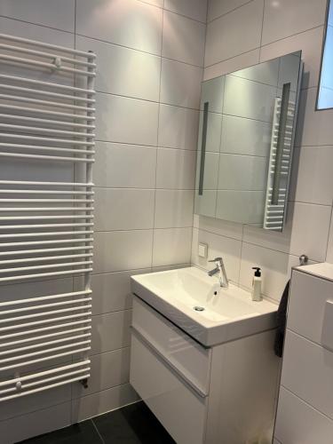 a white bathroom with a sink and a mirror at Huisje36 in Middelburg
