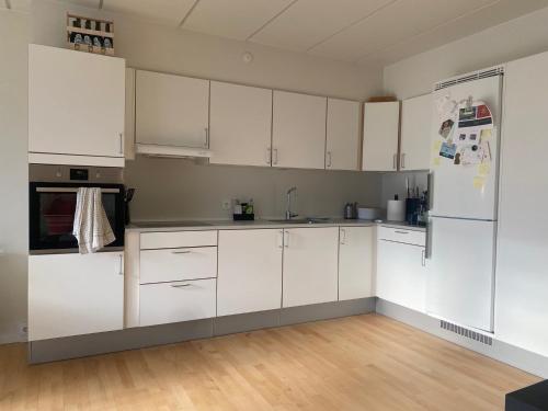  La cuisine est équipée de placards blancs et d'un réfrigérateur. dans l'établissement Hyggeligt lille værelse, à Odense