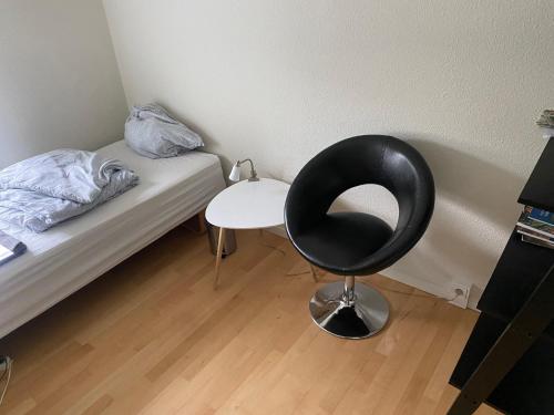a bedroom with a black chair next to a bed at Hyggeligt lille værelse in Odense