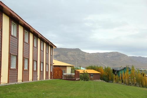 a building with a grassy yard next to a building at Hotel Picos Del Sur in El Calafate