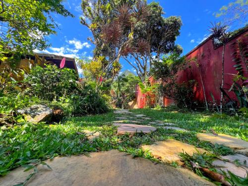 a garden with a red building and grass and trees at Condomínio Aldeia in Abraão