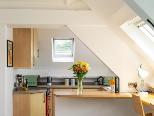 a kitchen with a vase of flowers on a counter at Pass the Keys Tranquil cosy apartment in centre of Avening in Avening