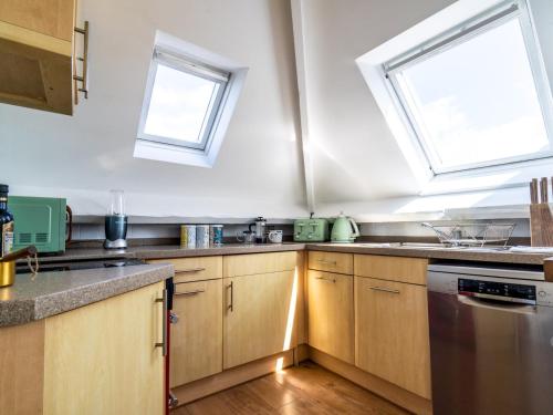 a kitchen with wooden cabinets and two windows at Pass the Keys Tranquil cosy apartment in centre of Avening in Avening