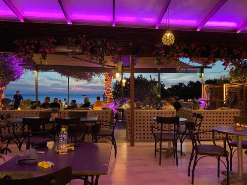 me gusta suite by the sea في أنافيسوس: مطعم فيه انوار ارجوانية والناس جالسين على الطاولات